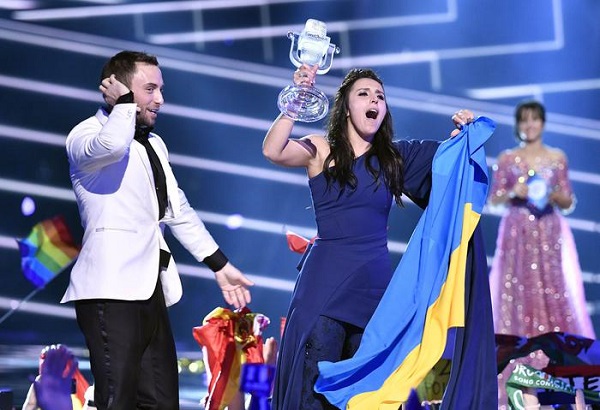 Ukraine's Jamala celebrates after receiving the trophy from co-host and 2015 Eurovision winner Mans Zelmerlow after winning the Eurovision Song Contest final with the song '1944' in Stockholm, Sweden, Sunday, May 15, 2016. (ANSA/AP Photo/Martin Meissner) 
